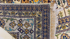 Macro close-up of hand-knotted underside of Belzhiki Gandumak Afghan carpet – showing individual knot density and weave structure, navy blue border with antique gold floral motifs, teal medallion detail, natural cotton fringe, evidence of 40×40 knots per 10cm craftsmanship, Sheberghan Afghanistan