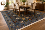 Belzhiki & Regional Mirror Design Afghan carpet styled in a traditional dining room – slate-blue botanical panel field with ivory fringe beneath a six-seat walnut dining table, brass candlesticks and gold vase centrepiece, warm hardwood floor, natural window light and classic sideboard, 202×301cm hand-knotted Turkman wool, Golden Loom Afghanistan
