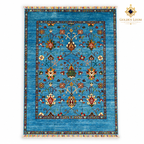 Top view of turquoise hand-knotted Afghan wool carpet with botanical motifs, colourful fringes and Golden Loom Afghanistan logo