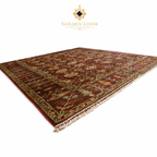 Afghan hand-knotted area rug in brown and gold with floral pattern, shown at angle to display pile depth, texture, and ivory fringe