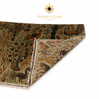 A folded view of a Golden Loom Afghanistan area rug showing its detailed multicolor pattern with peacocks, birds, and floral motifs on a beige background, set against a plain white background with the Golden Loom logo at the top.
