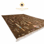 A rectangular Afghan area rug by Golden Loom, featuring a dark brown background with intricate multicolor floral and tree motifs, finished with white fringed edges, shown on a white background with the Golden Loom brand logo above.