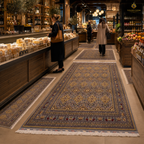 Hand-knotted Afghan runner carpets in grey and gold laid across a warm-lit artisan market corridor with wooden shelving and shoppers