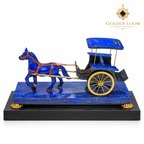 Handcrafted lapis lazuli horse-and-carriage sculpture with brass wheels displayed on a black wooden plinth against a white background.