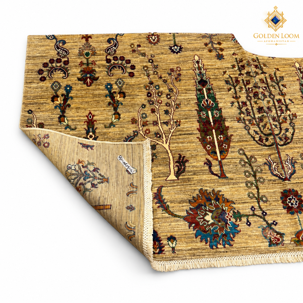 Folded corner of a golden-beige Afghan carpet showing its botanical pattern, woven backing and fringed end