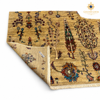 Folded corner of a golden-beige Afghan carpet showing its botanical pattern, woven backing and fringed end