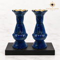 Pair of handcrafted lapis lazuli vases with brass-lined scalloped rims displayed on black wood against a white background.