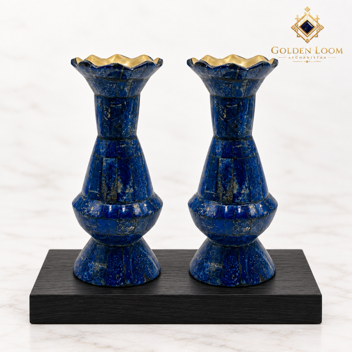 Pair of handcrafted lapis lazuli vases with brass-lined scalloped rims displayed on black wood against a white background.