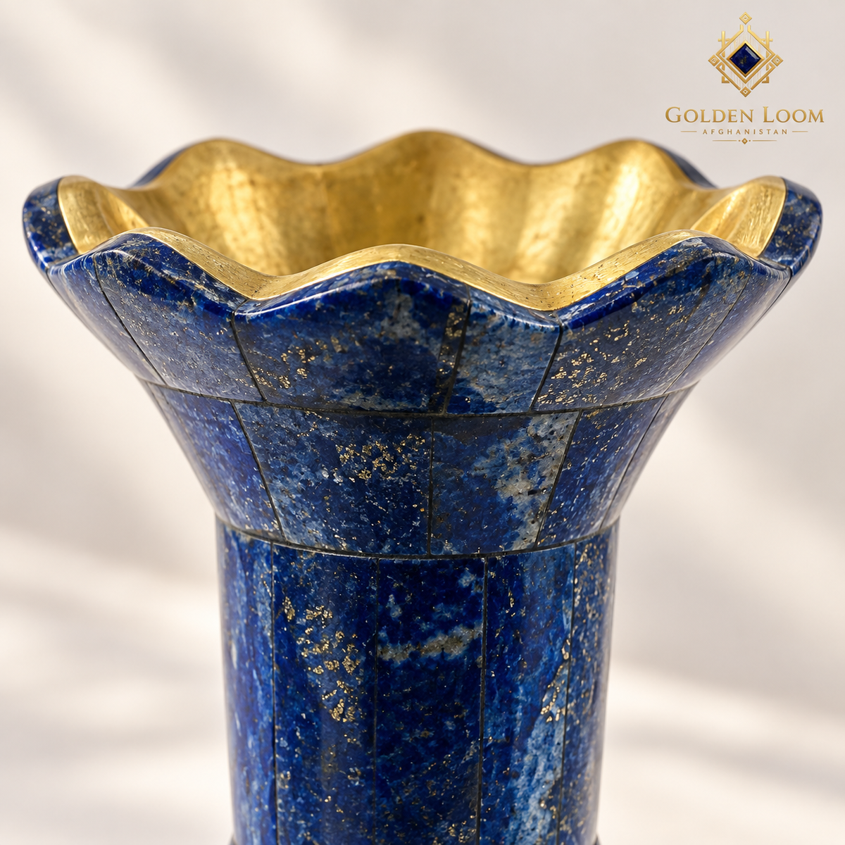 Close-up of genuine blue lapis lazuli, natural mineral markings and the polished brass-lined scalloped vase rim.