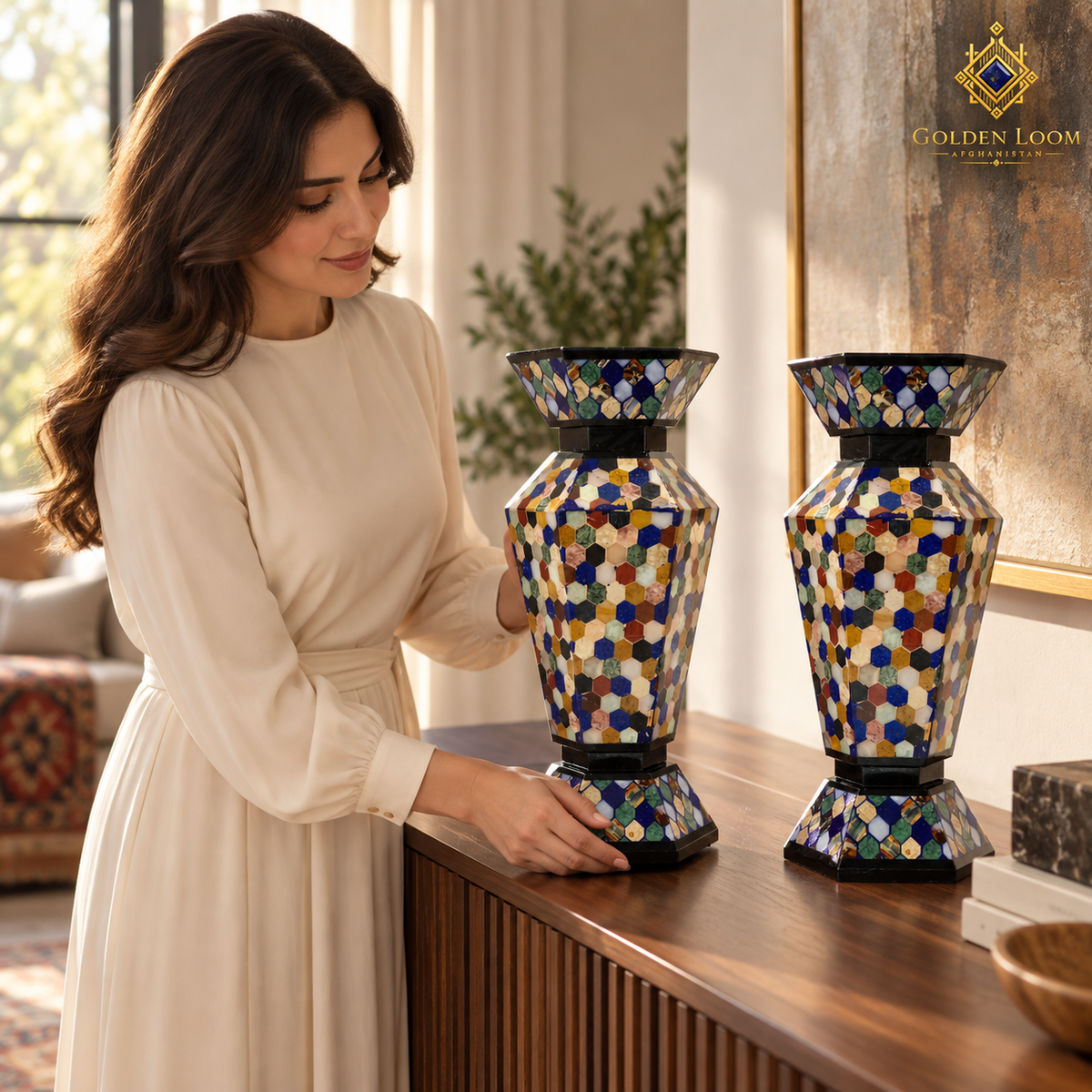 Woman carefully arranging a pair of handcrafted mosaic stone vases on a walnut console.