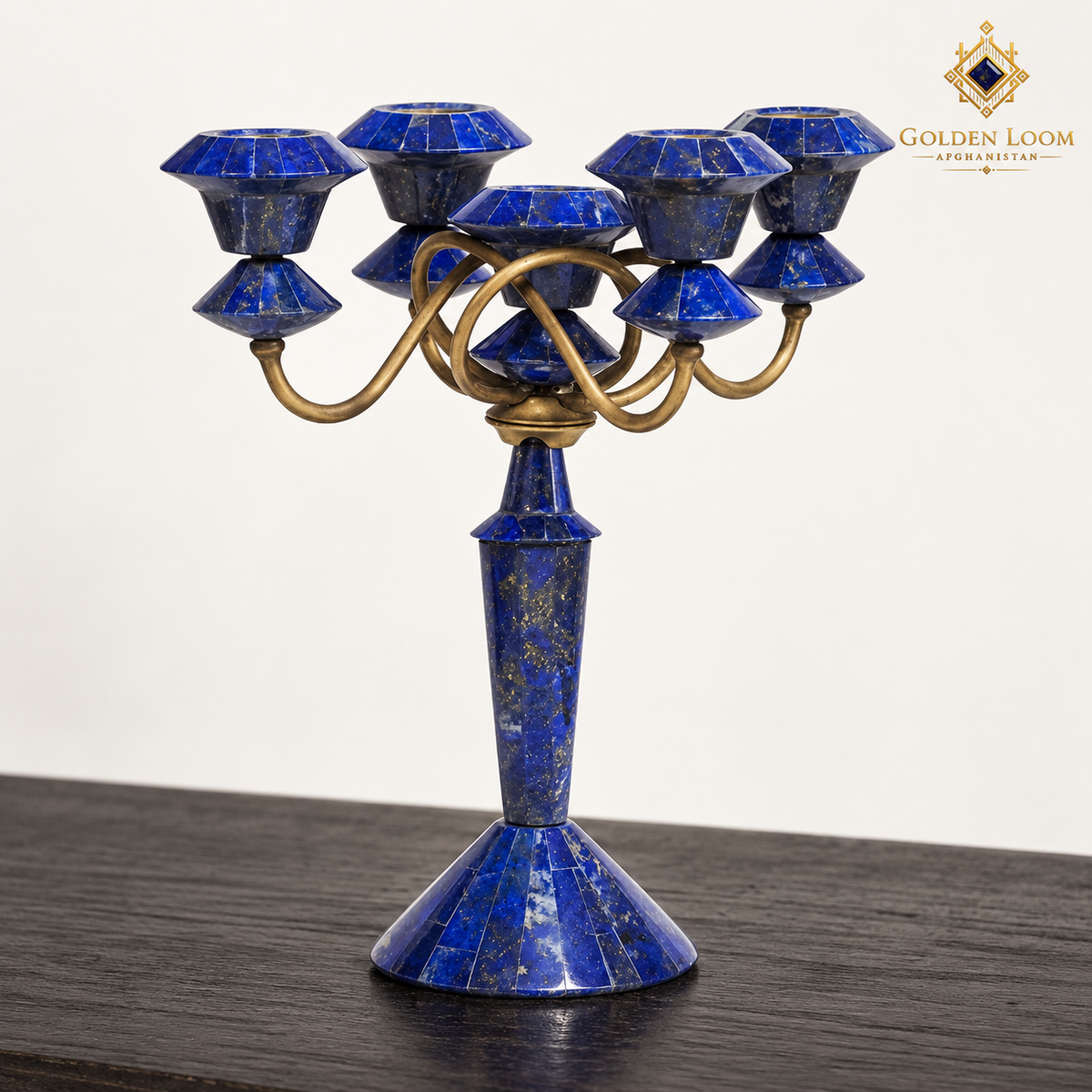 Three-quarter view of two handcrafted lapis candelabra showing five candle cups, curved brass arms and faceted stone bases