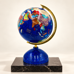 Handcrafted Afghan gemstone globe with lapis lazuli oceans and brass meridian on a black marble plinth.