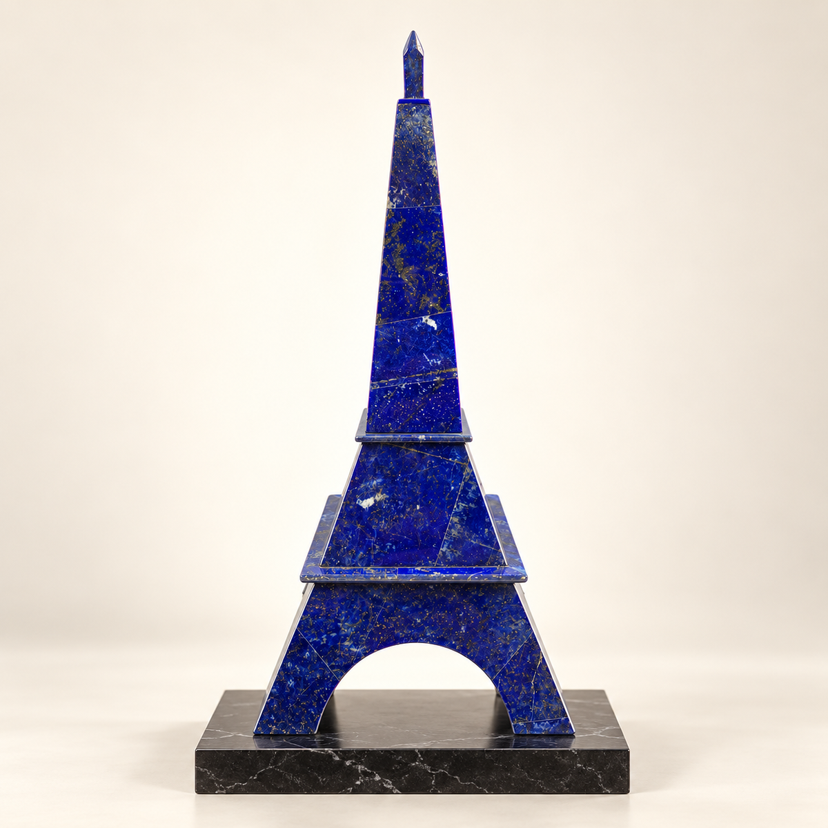 Handcrafted lapis lazuli Eiffel Tower sculpture displayed on a black marble plinth against an ivory background.