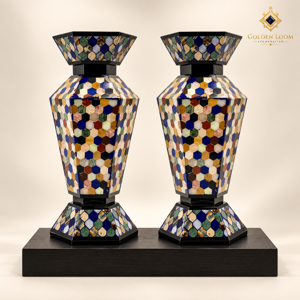 Pair of handcrafted six-sided mosaic stone vases displayed on a black wood plinth.
