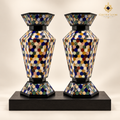 Pair of handcrafted six-sided mosaic stone vases displayed on a black wood plinth.