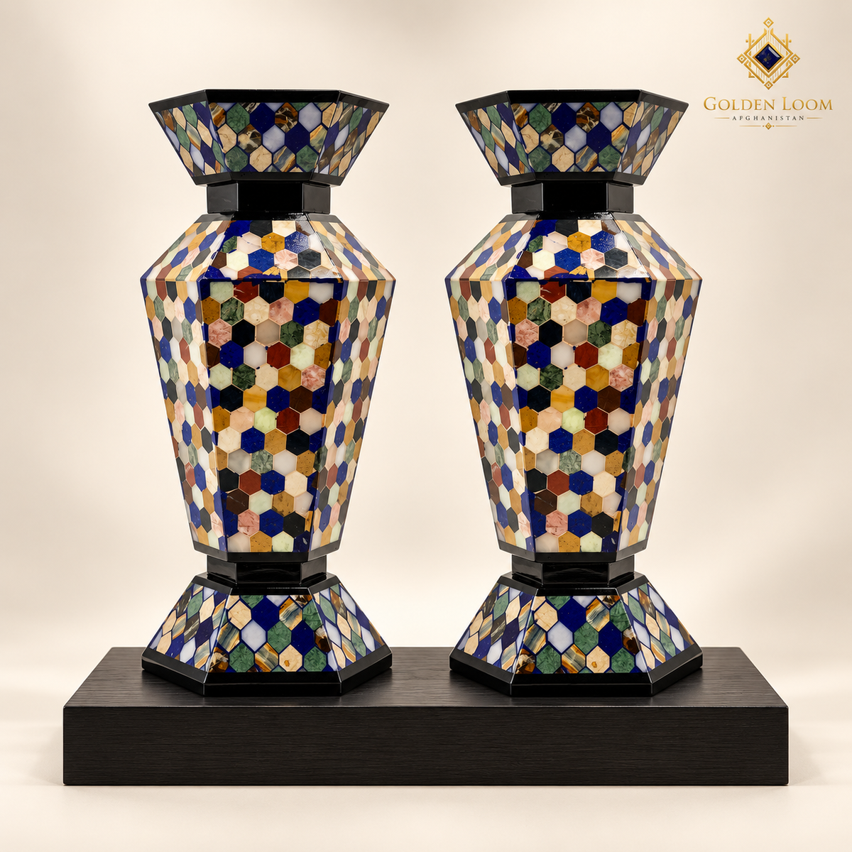 Pair of handcrafted six-sided mosaic stone vases displayed on a black wood plinth.
