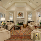 Large handwoven Afghan area rug with medallion design in red and gold anchoring a luxury living room with cream sofas and fireplace