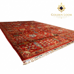 Afghan hand-knotted Chobi rug in crimson red with botanical floral design, angled overhead view showing pile depth and hand-tied fringe — Golden Loom Afghanistan