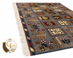 Belzhiki & Regional Mirror Design Afghan carpet – low-angle perspective view on white background showing slate-blue field with botanical panel grid, multicolored floral and cypress motifs in burgundy, ivory and gold, striped multi-color border with ivory hand-tied fringe, 202×301cm, 100% Turkman wool, hand-knotted in Qarqin, Jawzjan, Afghanistan, Golden Loom