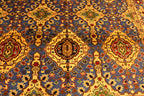 A high-angle, close-up shot showing the detailed, symmetrical geometric pattern of an oriental carpet dominated by vibrant blue, yellow, red, and green colors