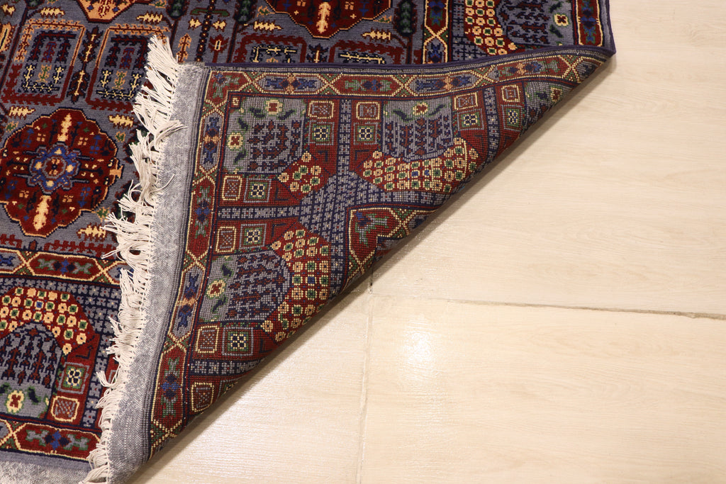 Close-up of the back of a hand-knotted Afghan rug, showing the detailed weave and quality craftsmanship of the intricate blue, red, and gold floral design