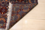 Close-up of the back of a hand-knotted Afghan rug, showing the detailed weave and quality craftsmanship of the intricate blue, red, and gold floral design