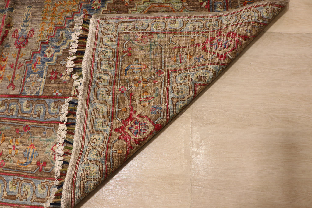 Detail of handwoven Afghan carpet corner folded back revealing dense knotted reverse with intricate border pattern in red, blue, and taupe