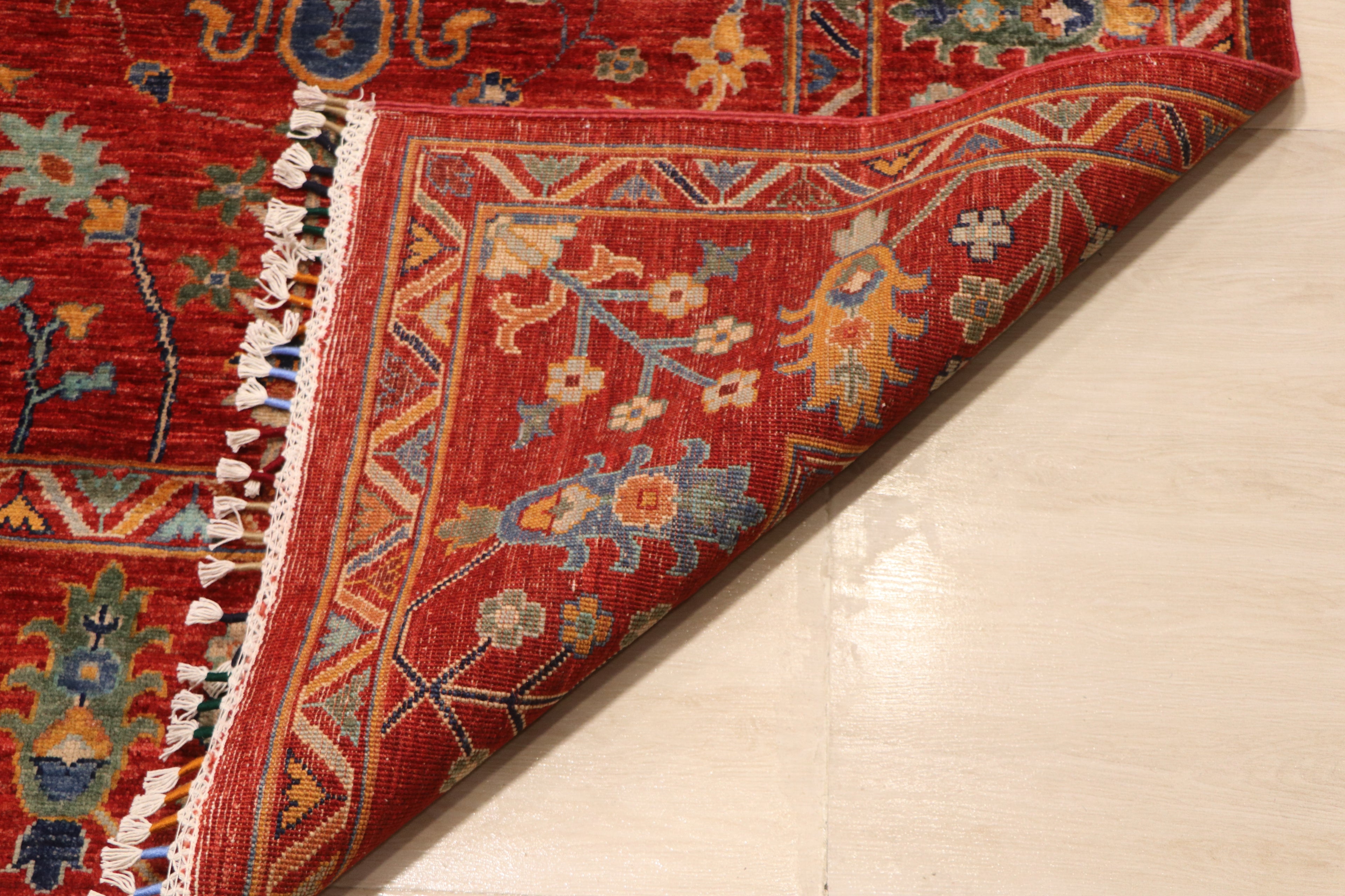 Close-up of Afghan hand-knotted Chobi rug corner fold showing dense wool pile, hand-tied fringe, and multicolor floral border detail — Golden Loom Afghanistan
