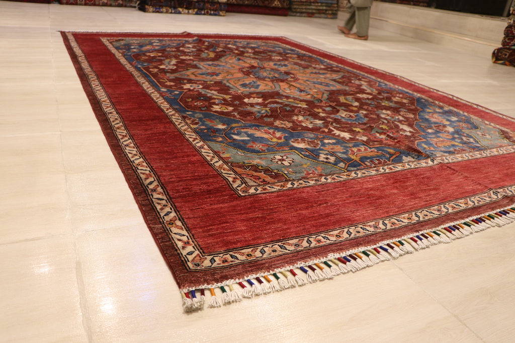Full view of Chobi Kashan Afghan hand-knotted wool carpet laid flat on white floor, showing red field, blue border, and ivory fringe