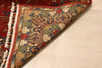 Corner of Sultani Chobi Afghan carpet folded back to reveal hand-knotted wool construction, white fringe, and richly detailed multi-color border with green, navy, and ivory tones