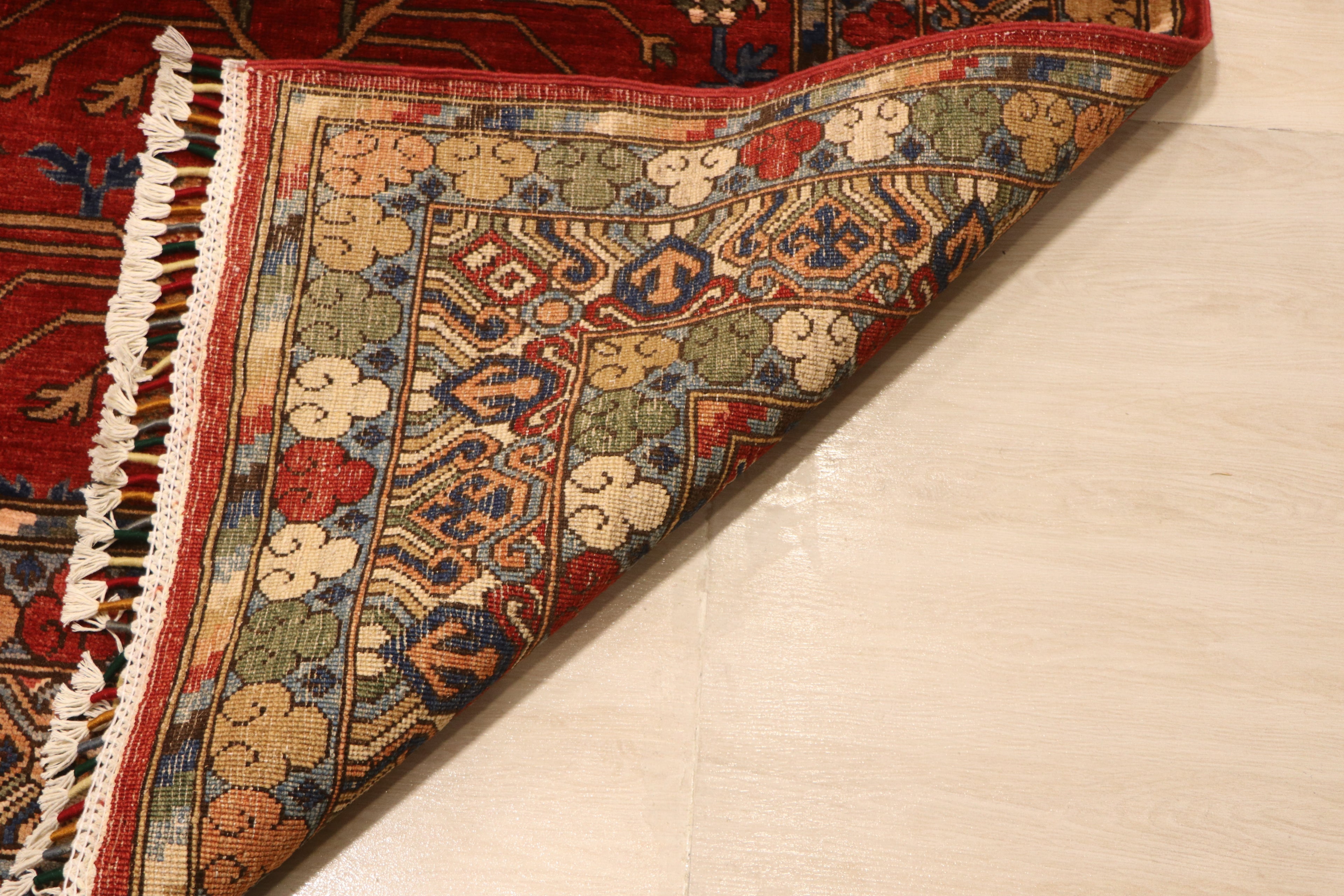 Corner of Sultani Chobi Afghan carpet folded back to reveal hand-knotted wool construction, white fringe, and richly detailed multi-color border with green, navy, and ivory tones