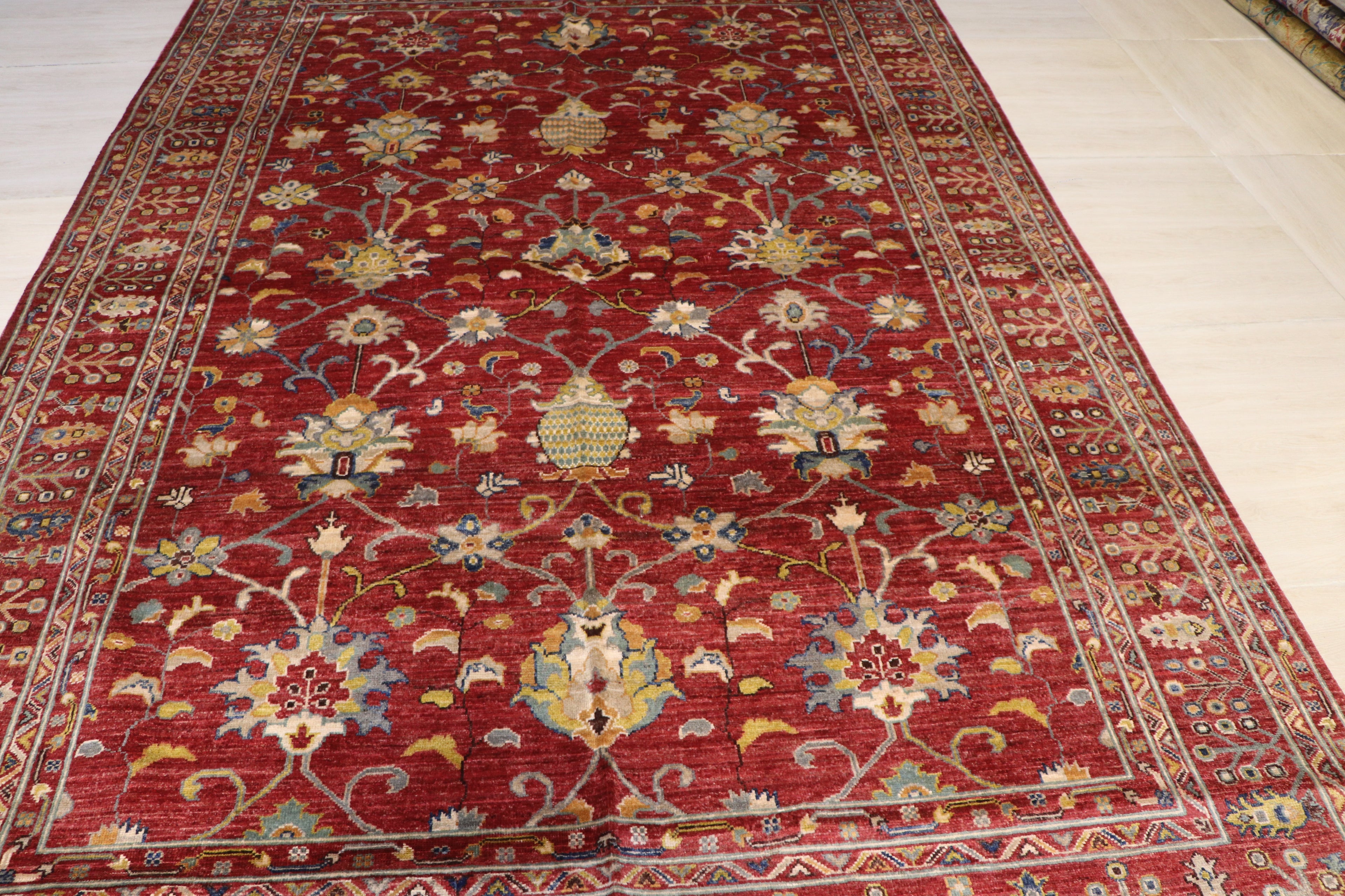Afghan hand-knotted wool rug with all-over red Ziegler floral pattern photographed on workshop floor, showing natural dye Color and fine knotting detail