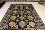 Hand-knotted Afghan area rug with black ground and traditional floral medallion design, displayed on showroom floor