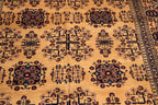 A close-up of a patterned rug with a warm tan background and dark navy and brown geometric floral motifs.