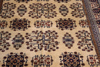 Close-up of the hand-knotted Afghan wool carpet showing detailed tree motifs, floral medallions and natural wool texture