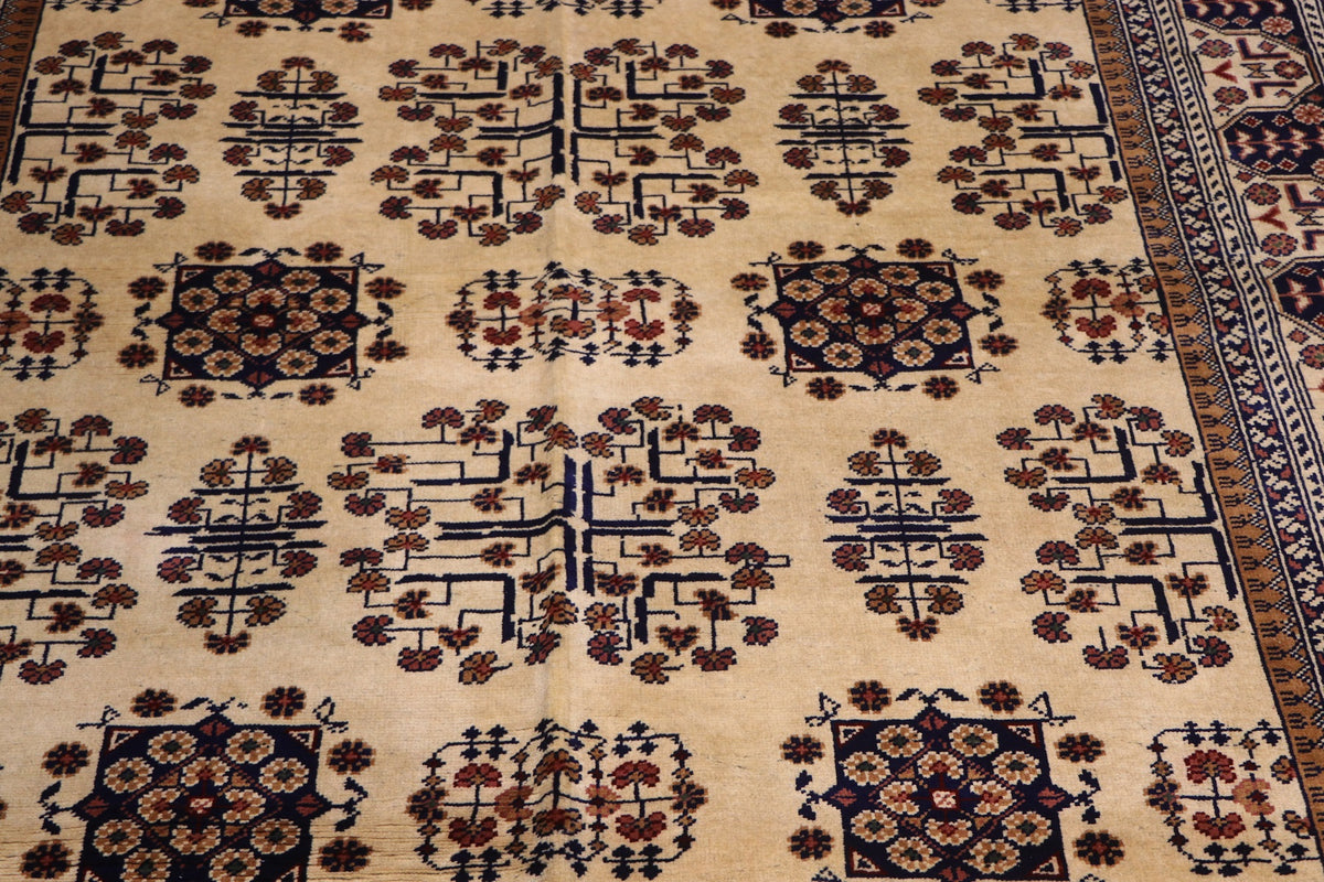 Close-up of the hand-knotted Afghan wool carpet showing detailed tree motifs, floral medallions and natural wool texture