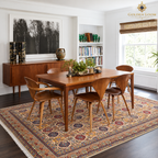 Colorful Afghan area rug styled beneath a wooden dining table and chairs in a bright modern dining room