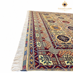 Close-up of an Afghan rug showing its intricate geometric border, multicolored woven details, and fringed edge