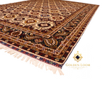 Close-up of hand-knotted Afghan rug border featuring intricate paisley and floral motifs in navy, burgundy, and gold with ivory fringe