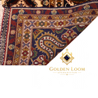 Folded corner of Afghan hand-knotted rug revealing dense wool pile and intricate navy and gold border with floral vine pattern