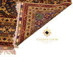 Reverse side of a hand-knotted Afghan rug revealing tight knot construction, with visible border detail in gold, crimson, and green floral patterns and ivory fringe