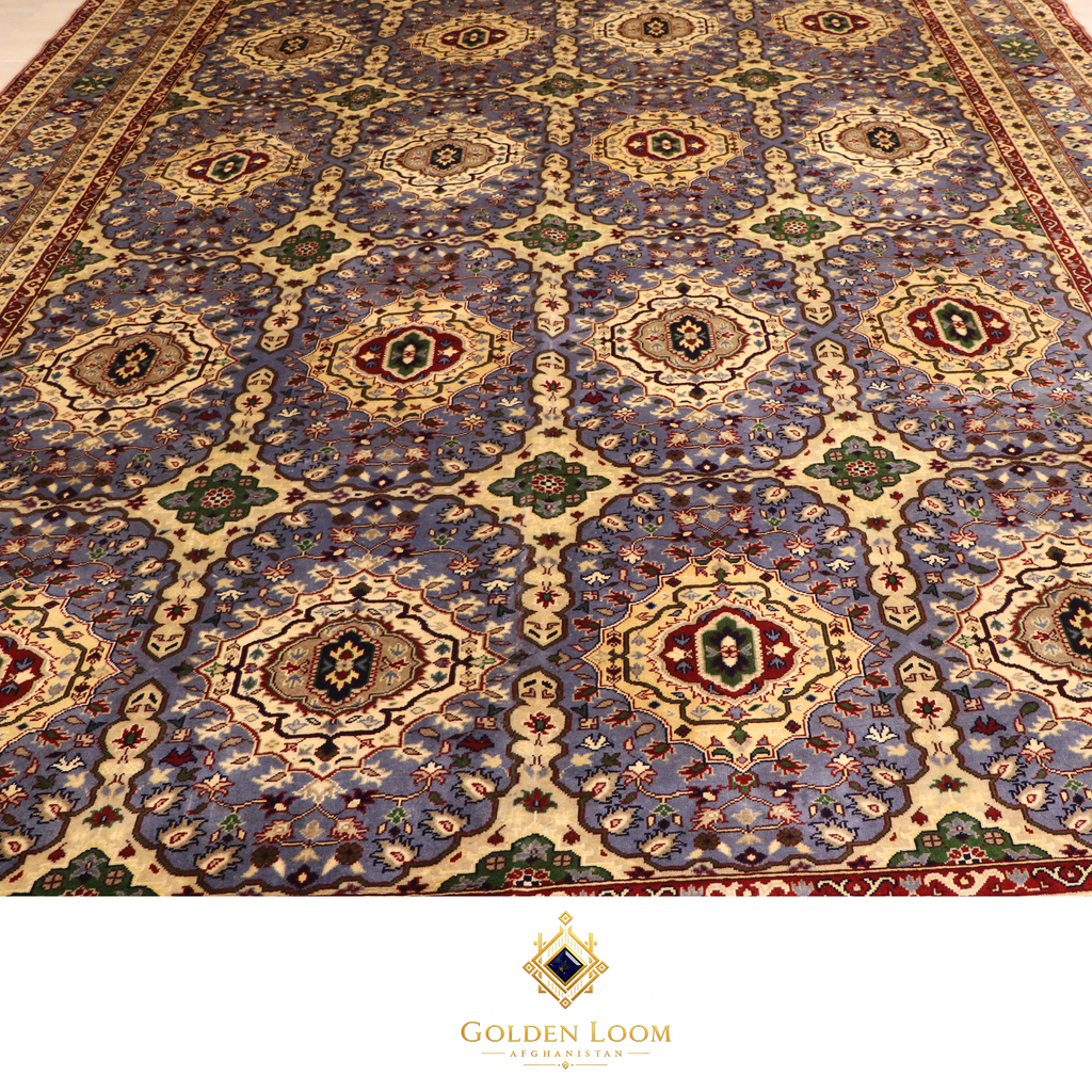 Close-up of the all-over field pattern of a hand-knotted Afghan rug featuring repeating octagonal medallions in ivory on a slate blue ground with red and green floral accents