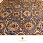Close-up of the all-over field pattern of a hand-knotted Afghan rug featuring repeating octagonal medallions in ivory on a slate blue ground with red and green floral accents