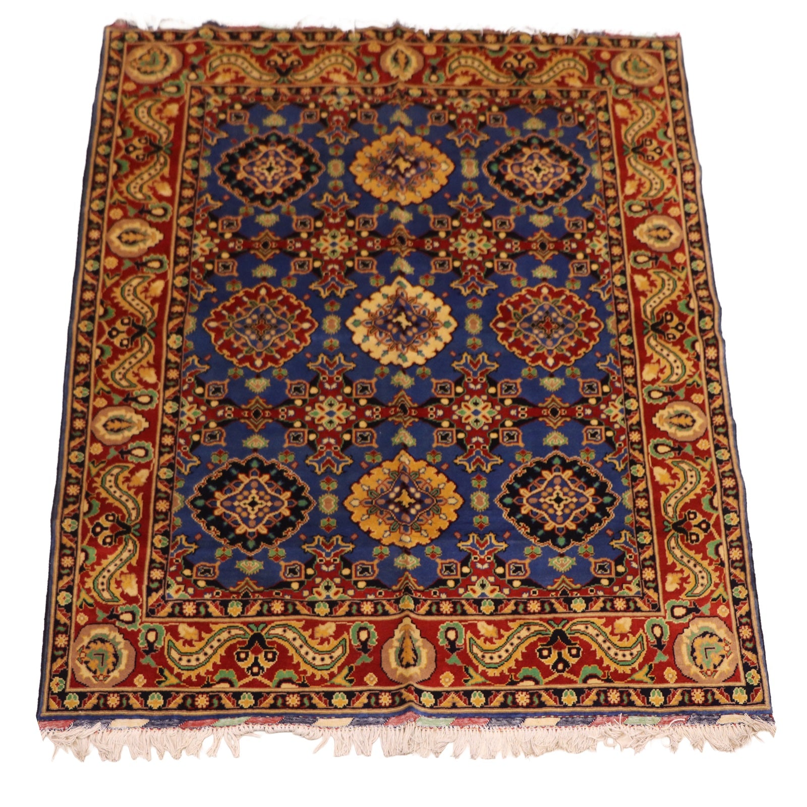 Hand-knotted Afghan wool rug featuring geometric medallions on indigo blue ground with deep red floral border and ivory fringe
