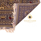 Close-up of hand-knotted Afghan carpet corner folded to reveal reverse weave, showing grey field with gold and navy floral motifs and ivory fringe