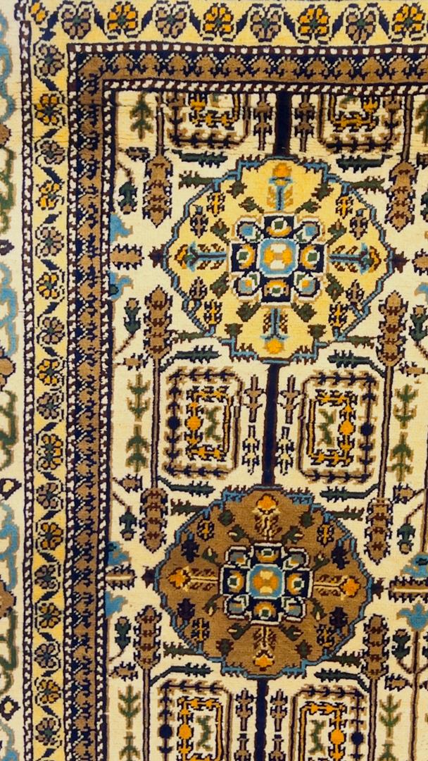 Close-up of Gandumak pattern detail on Belzhiki hand-knotted Afghan carpet – ivory field with geometric medallions in chocolate brown, teal blue and antique gold, floral border with navy and sage green accents, showcasing 40×40 knots per 10cm craftsmanship, Sheberghan Afghanistan
